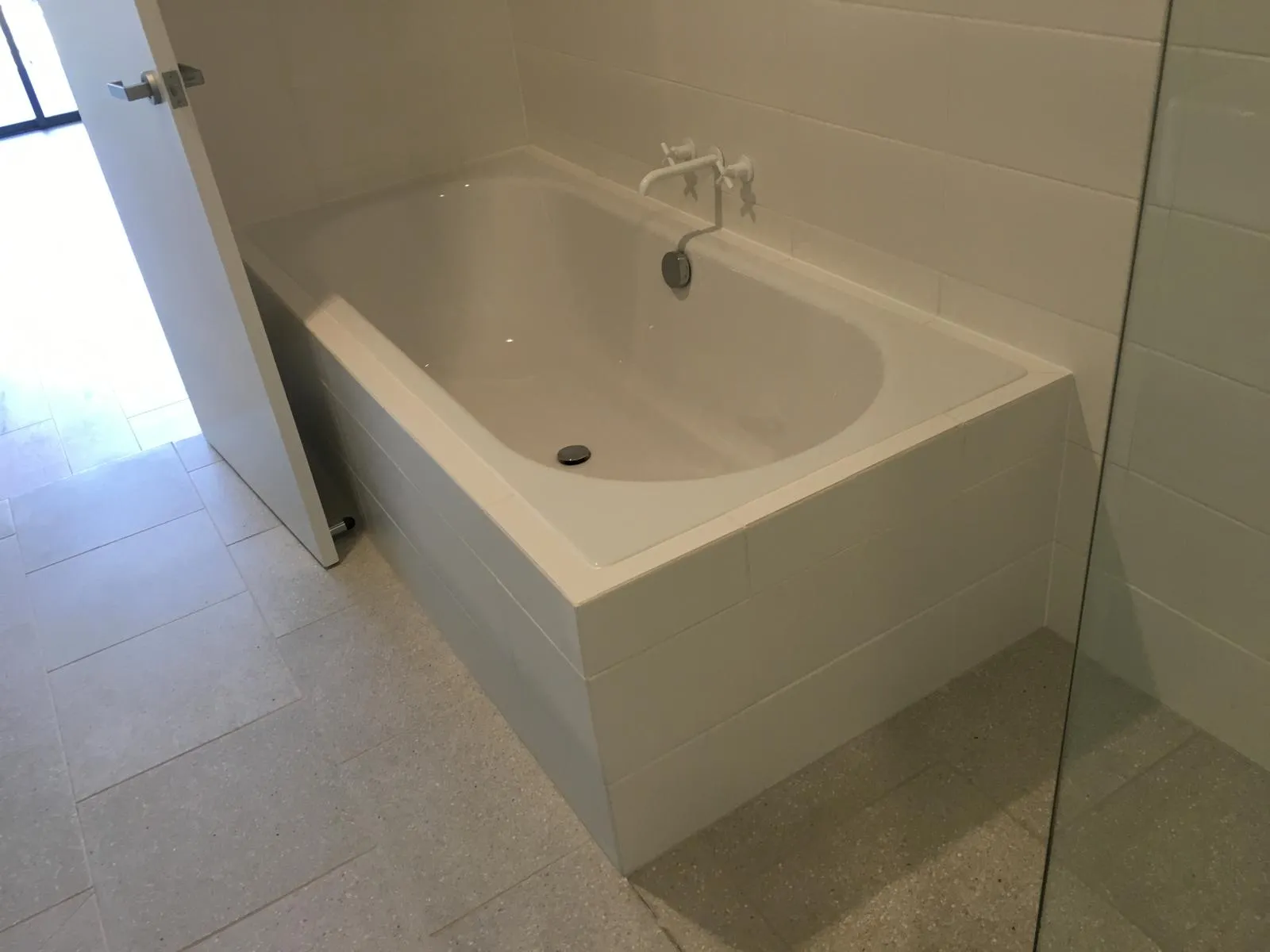 Built-in bath with a white subway tile surround and a terrazzo-look floor