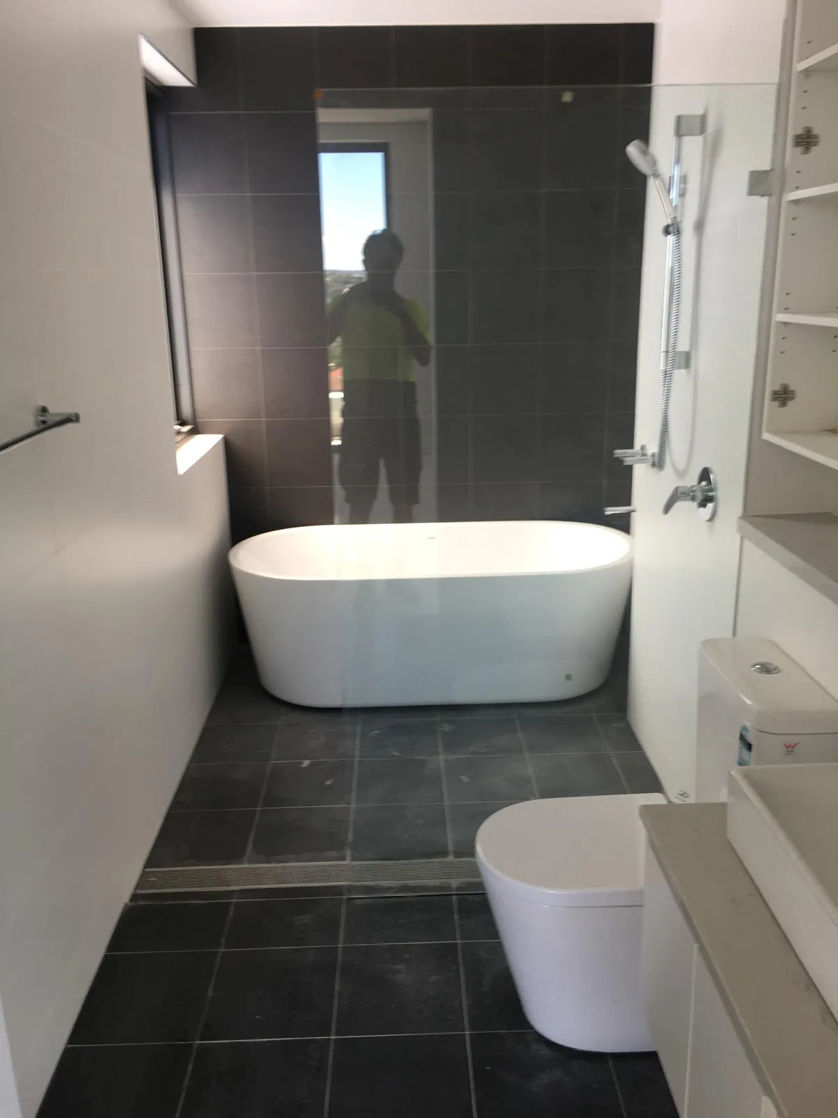 Bathroom with freestanding bath and dark floor tiles