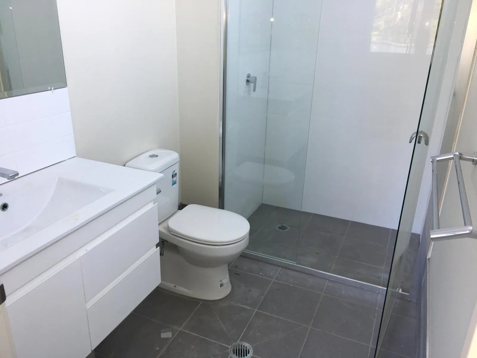 Ensuite with a white vanity, frameless glass shower and terrazzo-look floor tiles