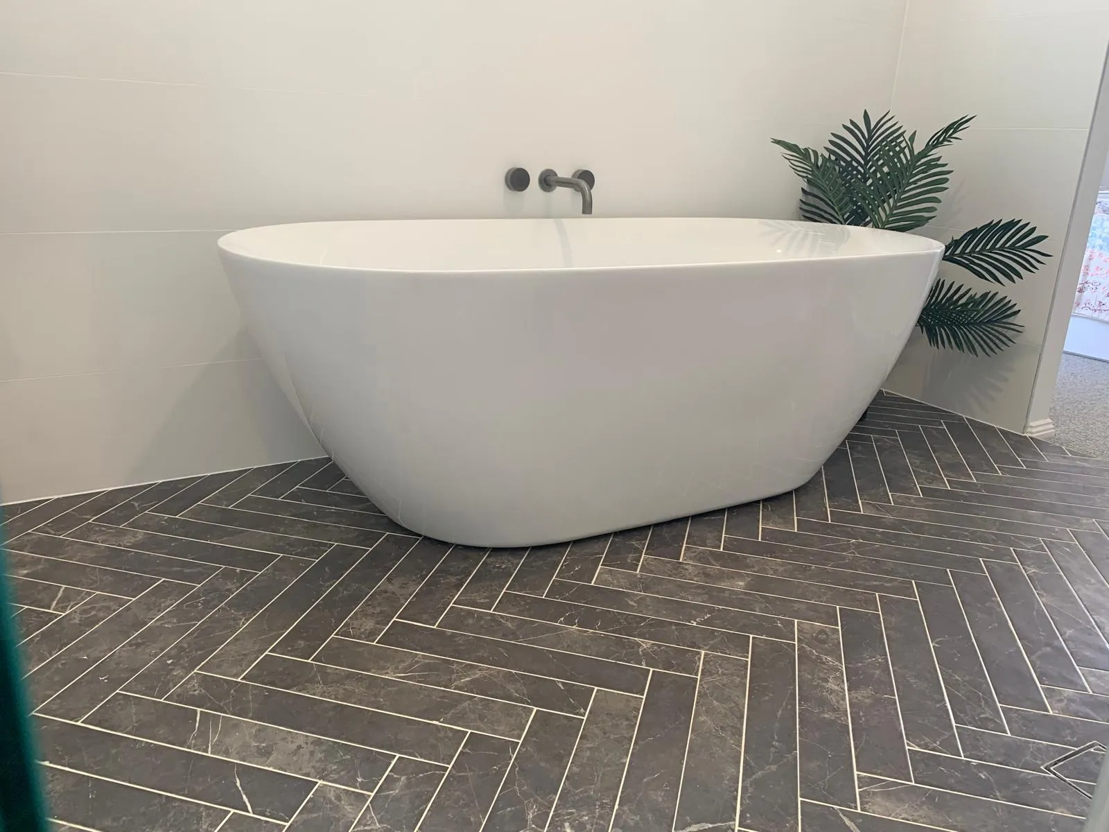 Freestanding bathtub against pale stone-look tiles