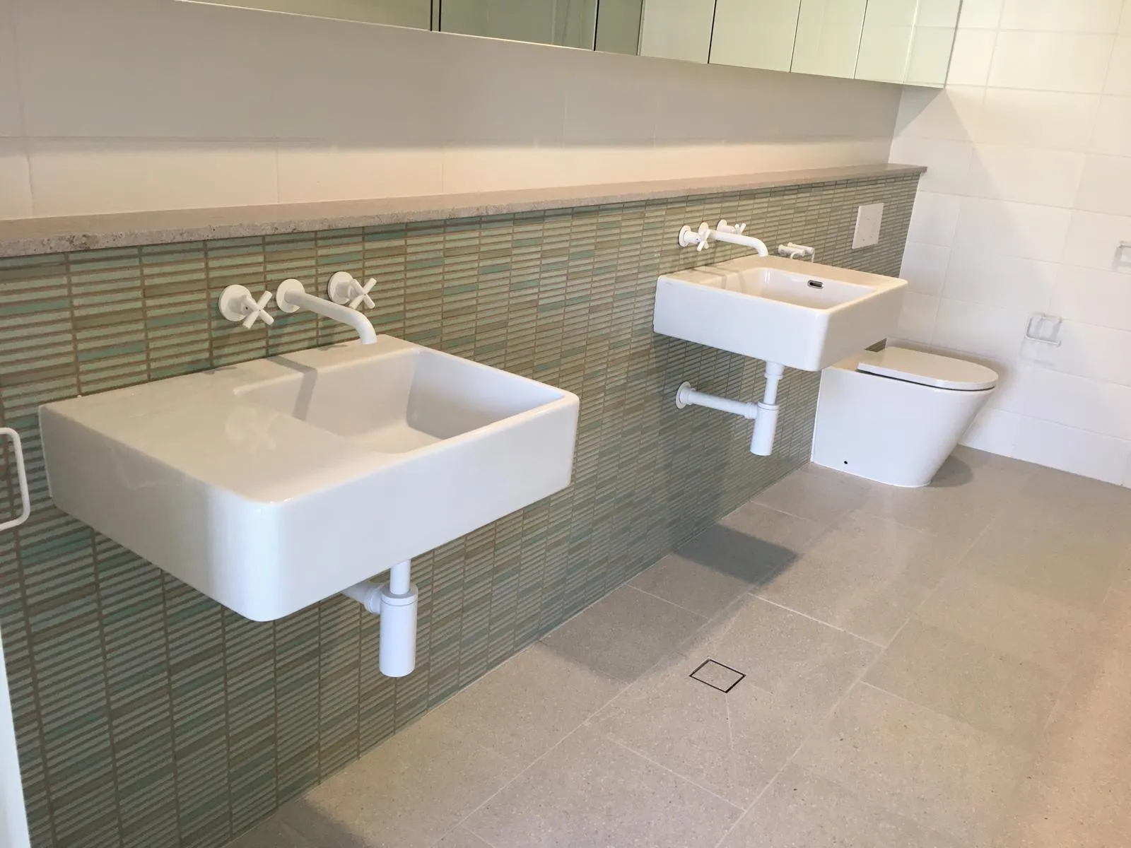 Bathroom with green tiled feature wall and twin wall-mounted basins