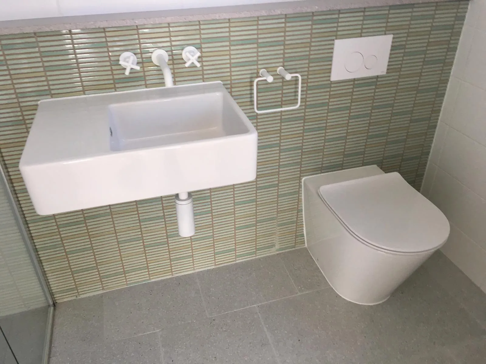 Bathroom vanity and toilet against green wall tiles
