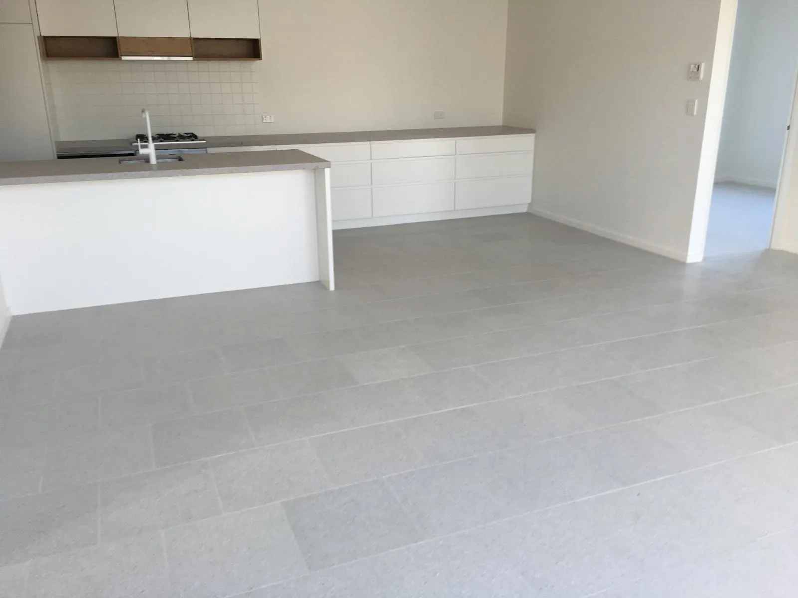 Bright interior with white kitchen and large-format floor tiles