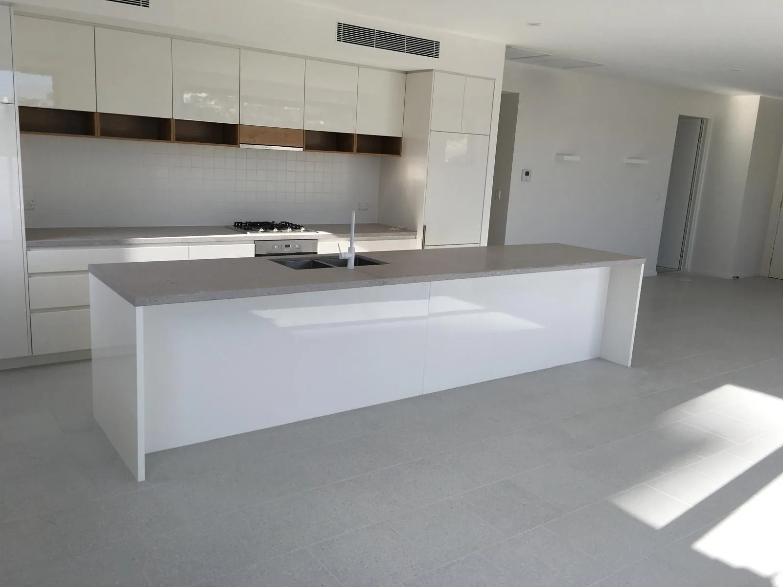 White kitchen with island bench and tiled floor