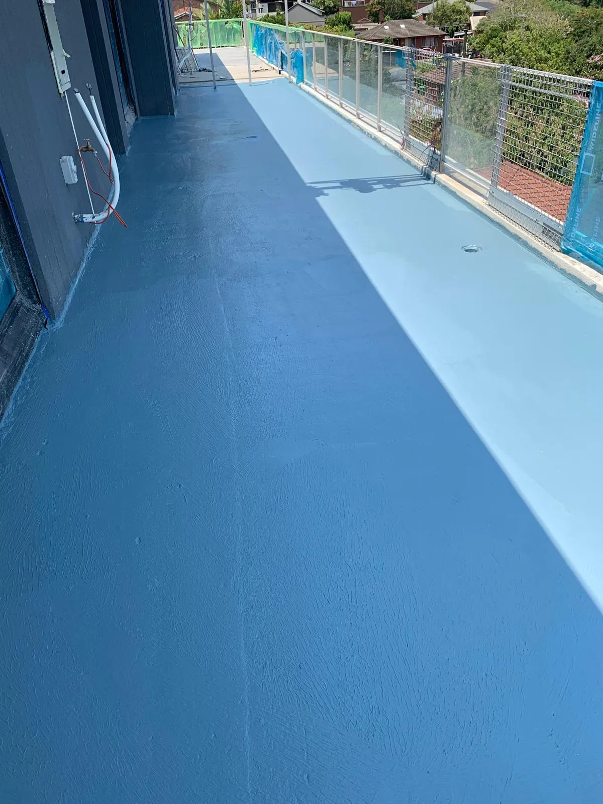 Finished blue outdoor surface beside a glass fence