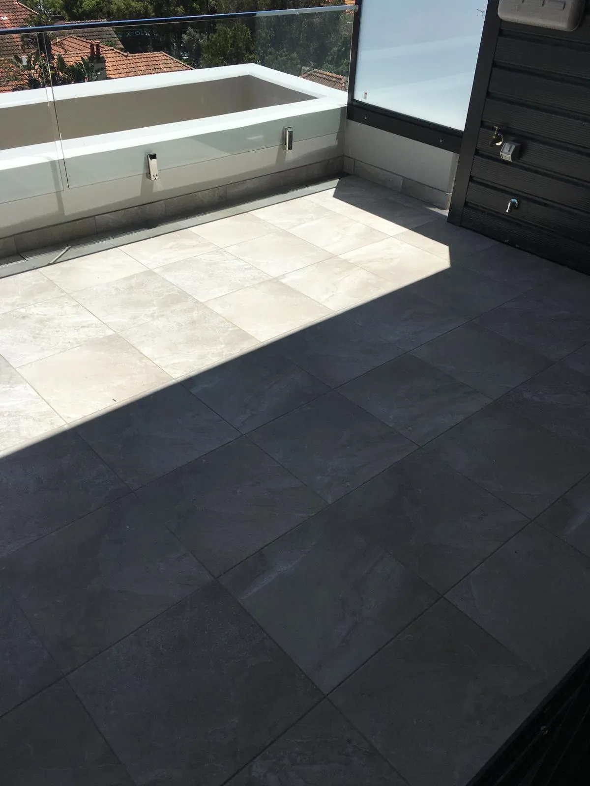 Rooftop terrace with two-tone stone-look tiles and a glass balustrade